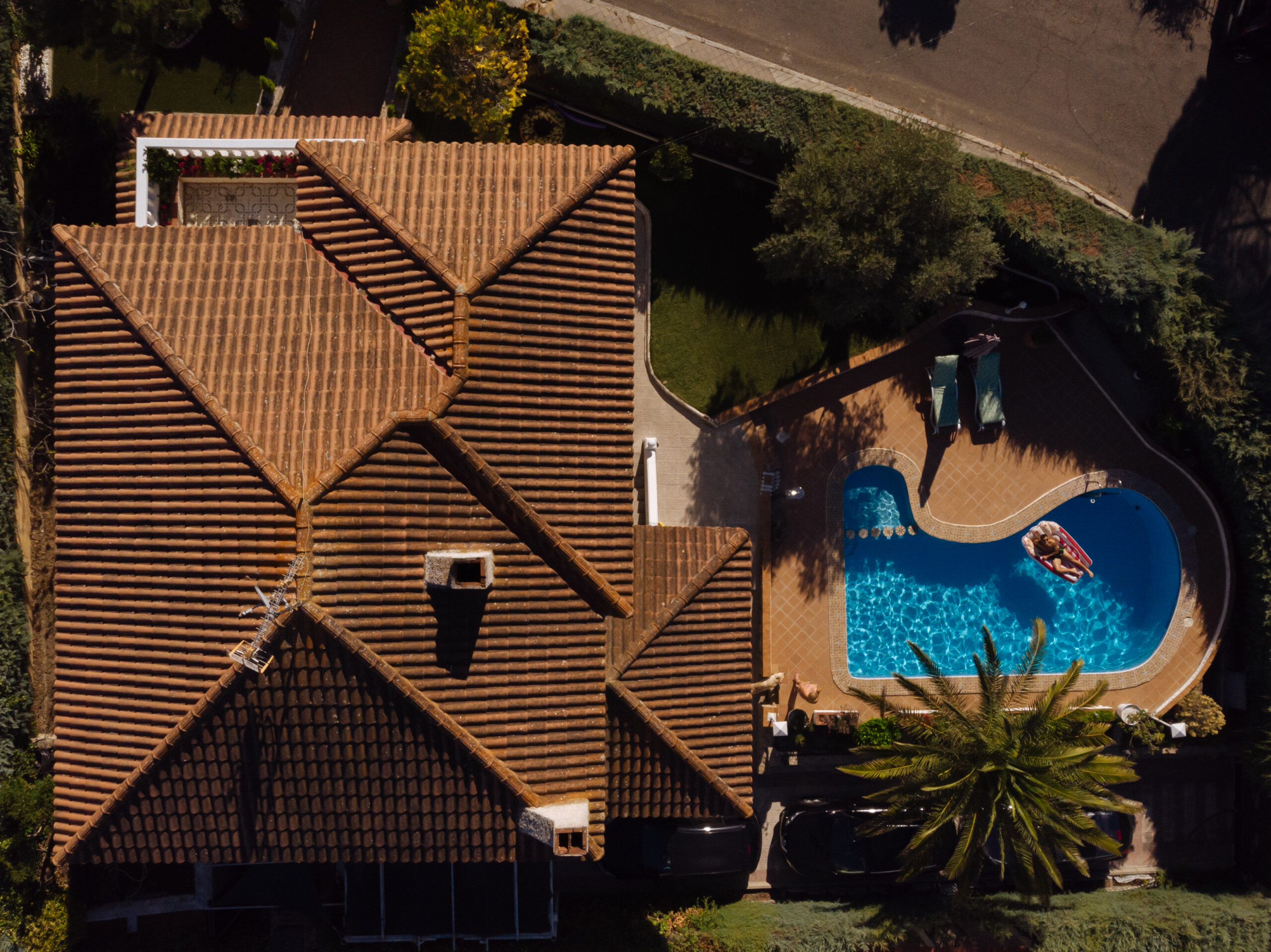 from above a man on beach mat in swimming pool of a villa house in a sunny day