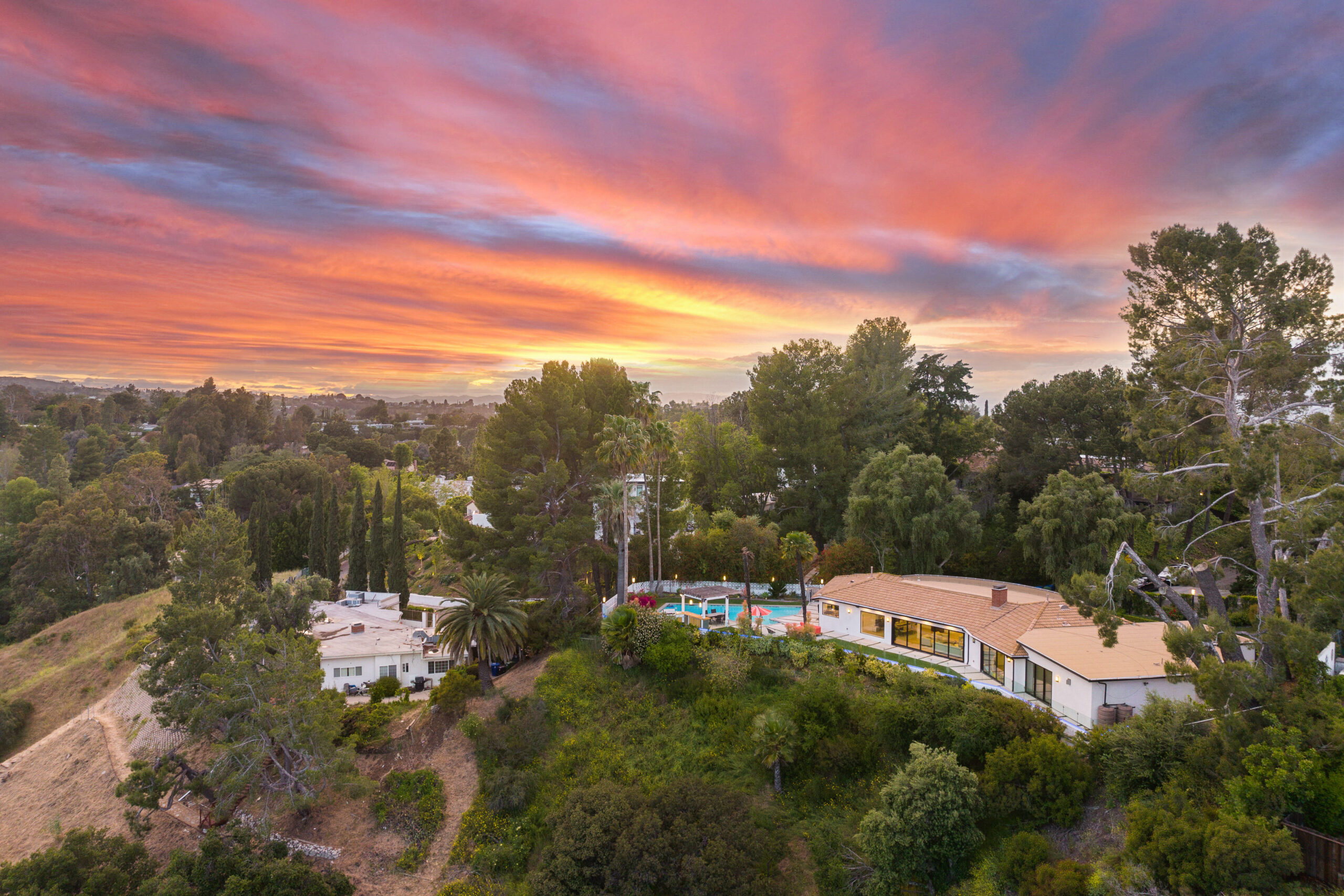 A stunning aerial view of a mountain retreat nestled in the hills, showcasing a breathtaking sunset